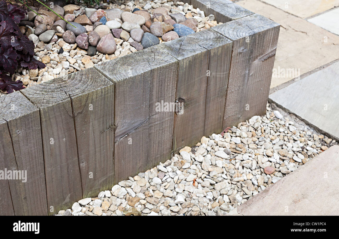 Behandeltes Holz verwendet, um erhöhte Blumenbeet mit dekorativen Steinen im heimischen Garten, Wales, Großbritannien zu machen Stockfoto