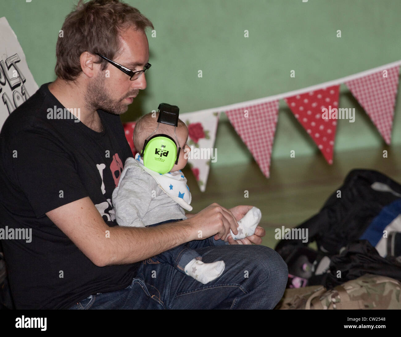 Ein Baby im Gehörschutz mit seinen Socken hochgezogen. Stockfoto