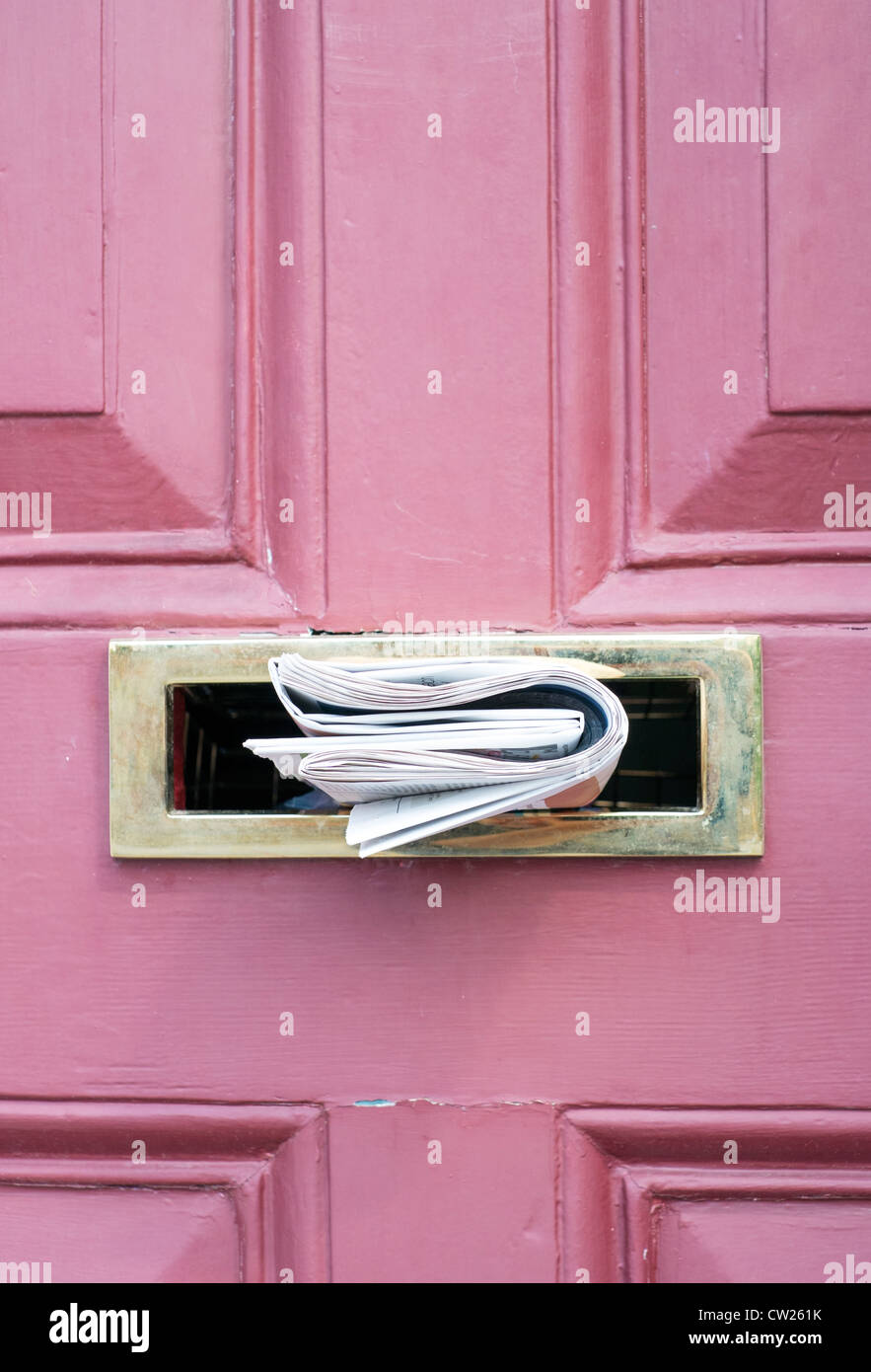 Zeitung im Briefkasten aus Messing in rosa Tür Stockfoto