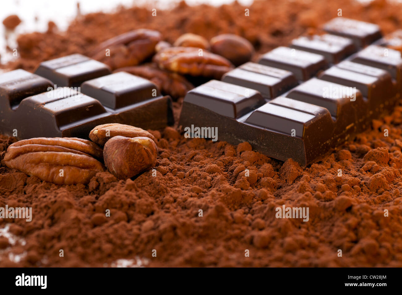 Schokoriegel, aufgeteilt in zwei Hälften mit Kakaopulver und Nüssen. Stockfoto