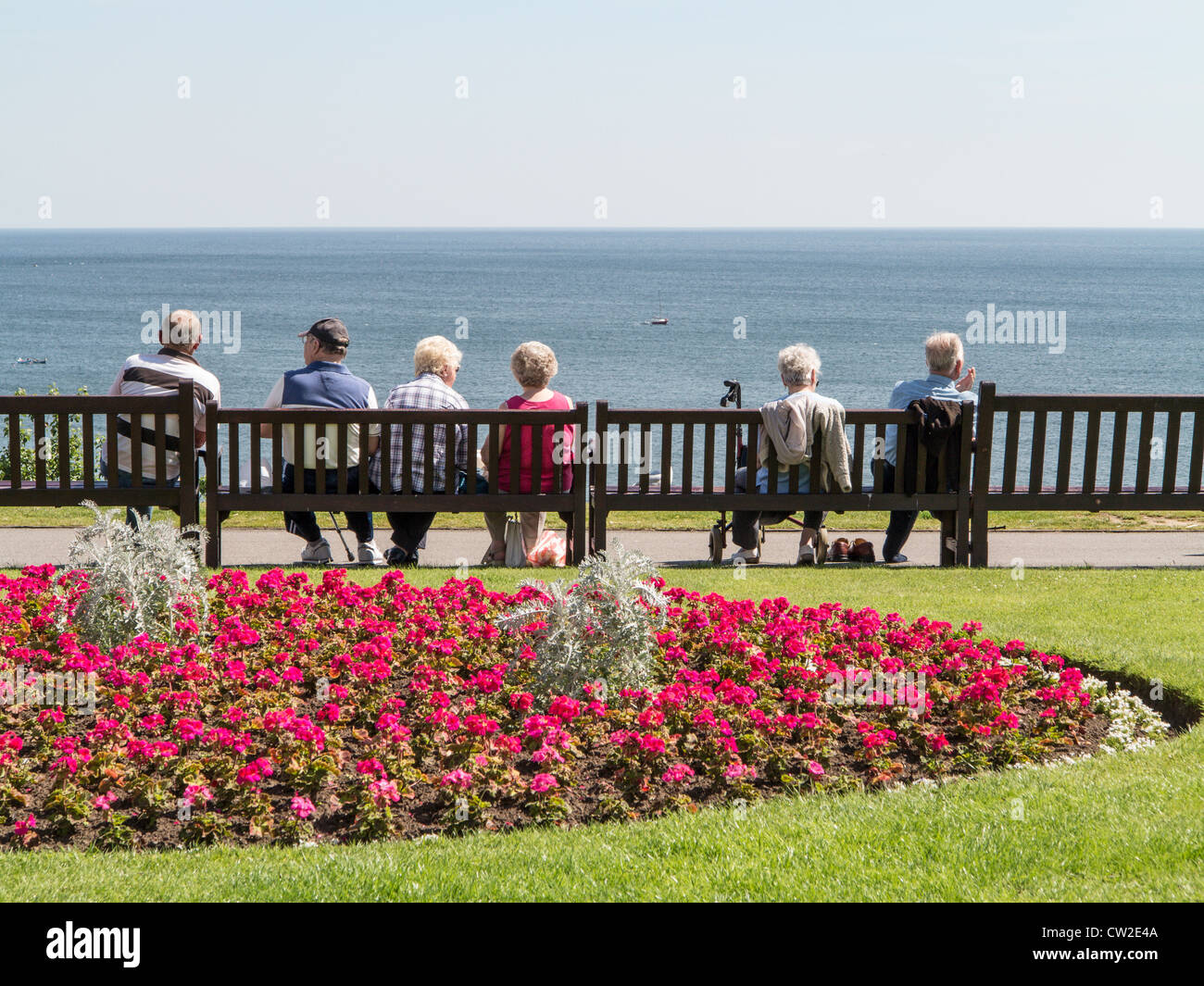 Rentner auf Bank mit Blick auf das Meer bei Filey Yorkshire UK Stockfoto
