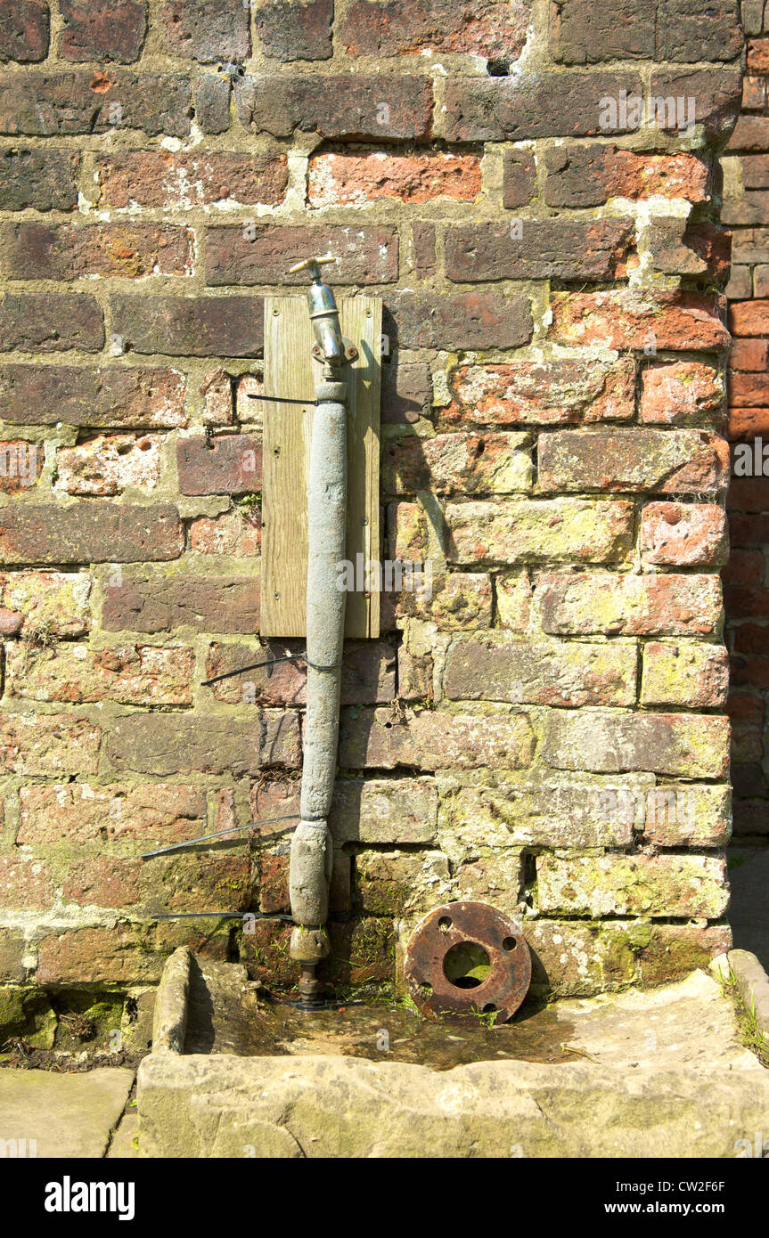 Wasserhahn in gegen alte Mauer Stockfoto