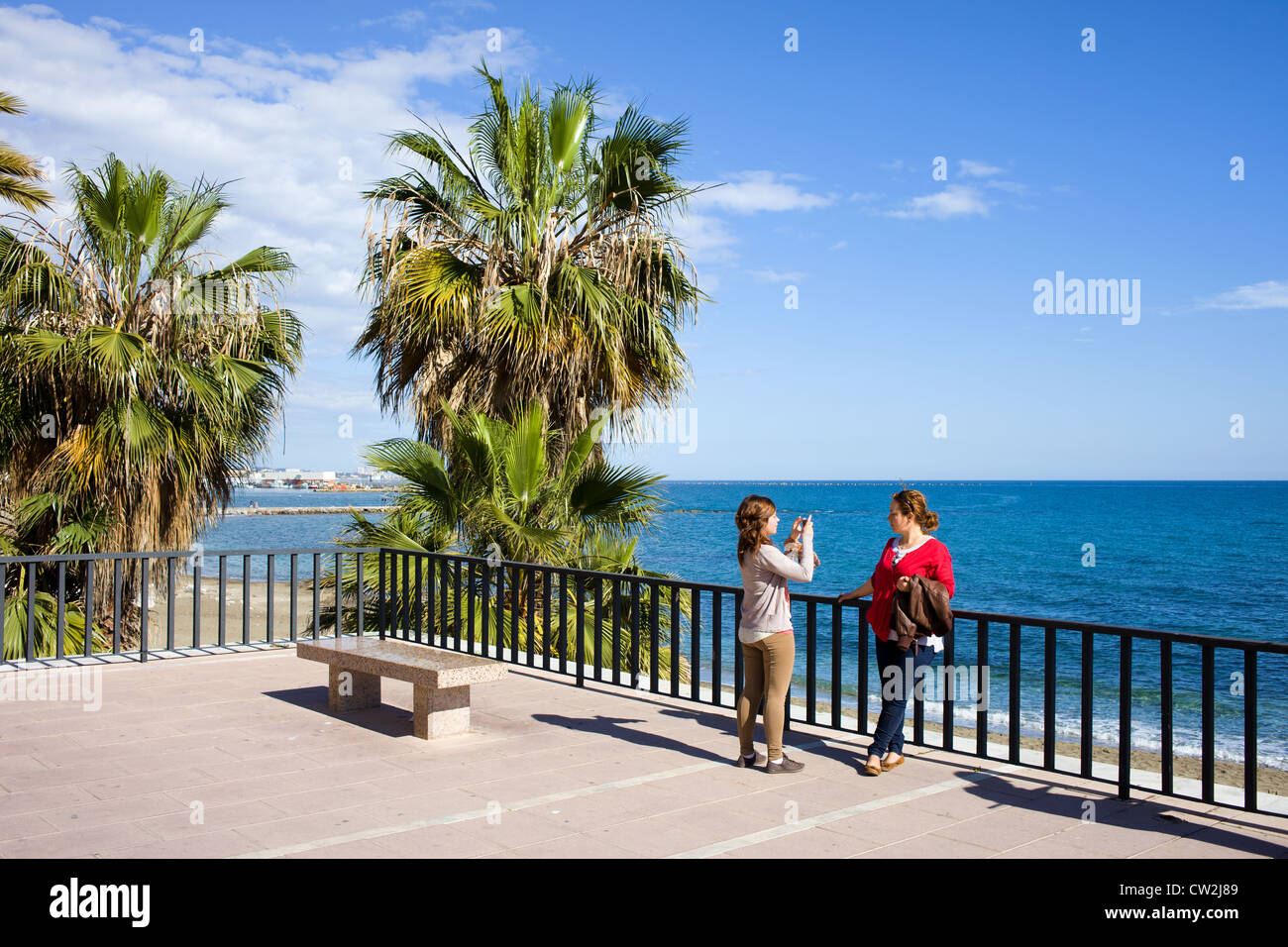Zwei Frauen fotografieren Speicher auf dem Meer Strandpromenade in Resort Stadt Marbella an der Costa Del Sol in Spanien, Süden Andalusiens. Stockfoto