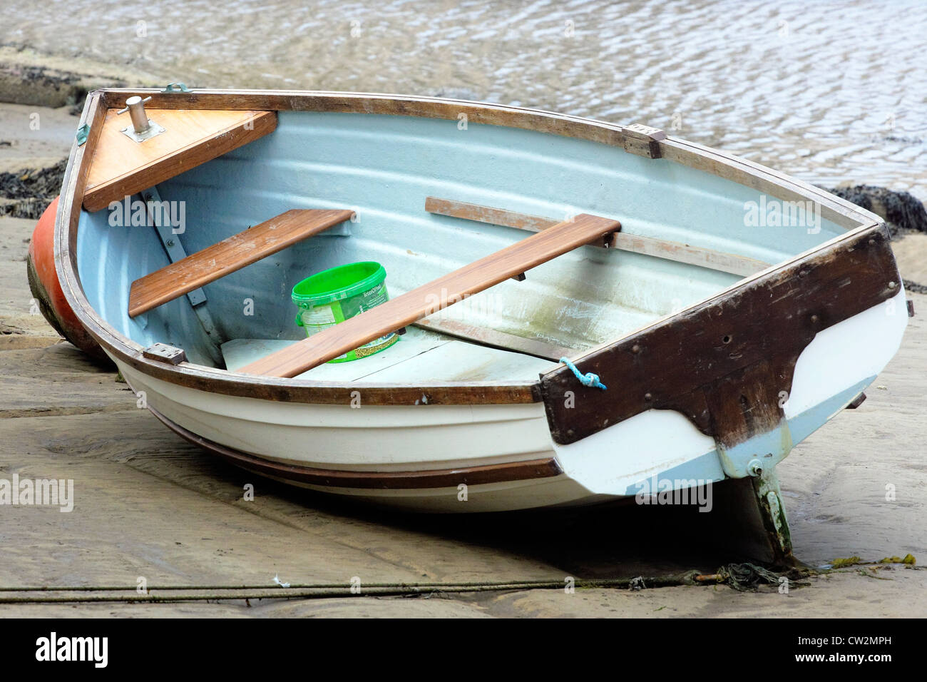 Ein kleines Ruderboot auf dem Tideline gestrandet. Stockfoto