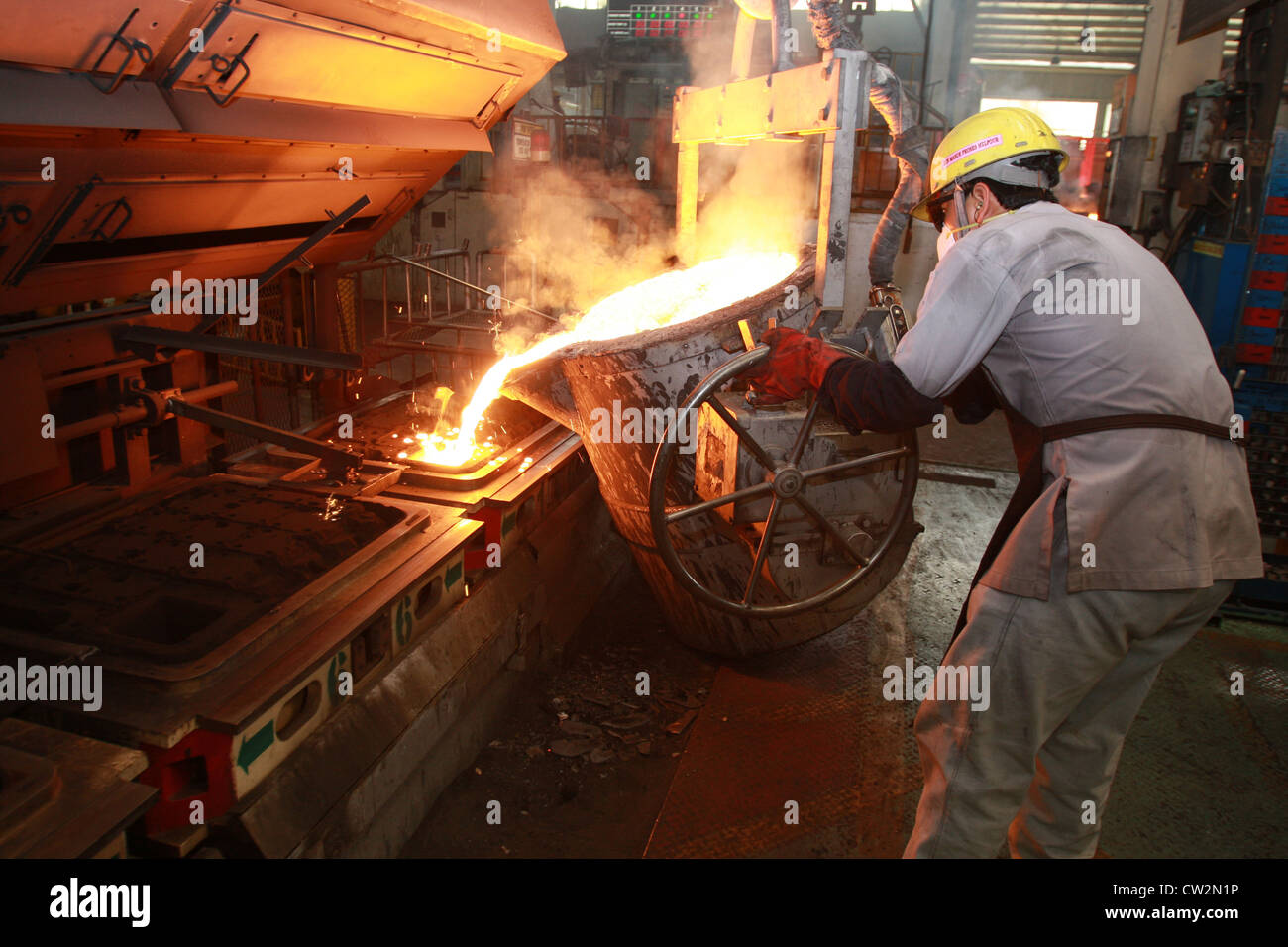 Ein Arbeiter gießt geschmolzenes Eisen zur Besetzung im Motorenwerk Stockfoto