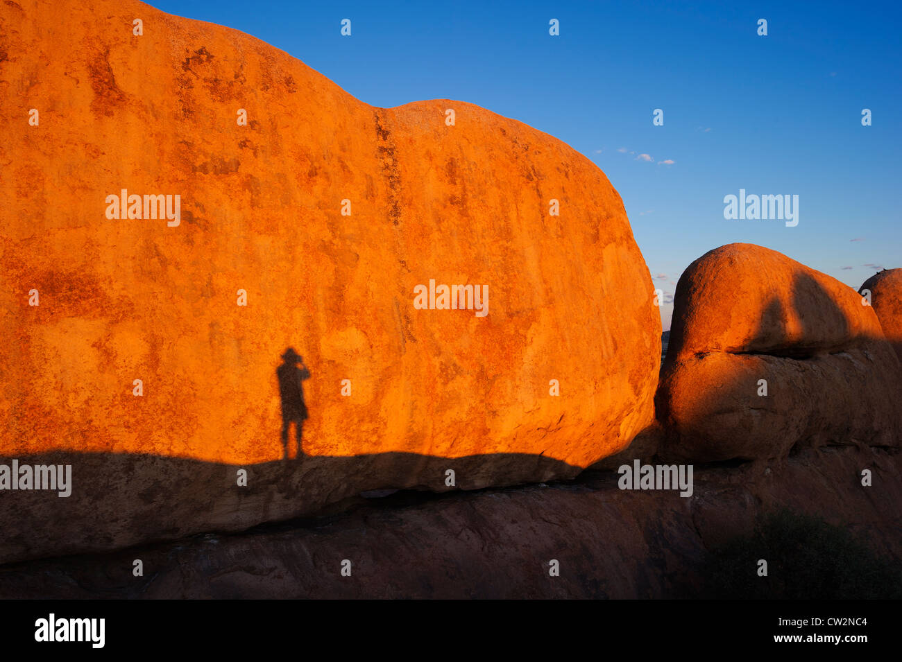 Schatten eines Mannes gegen Spizkoppe-Rock-Formation. Namib Desert.Namibia Stockfoto