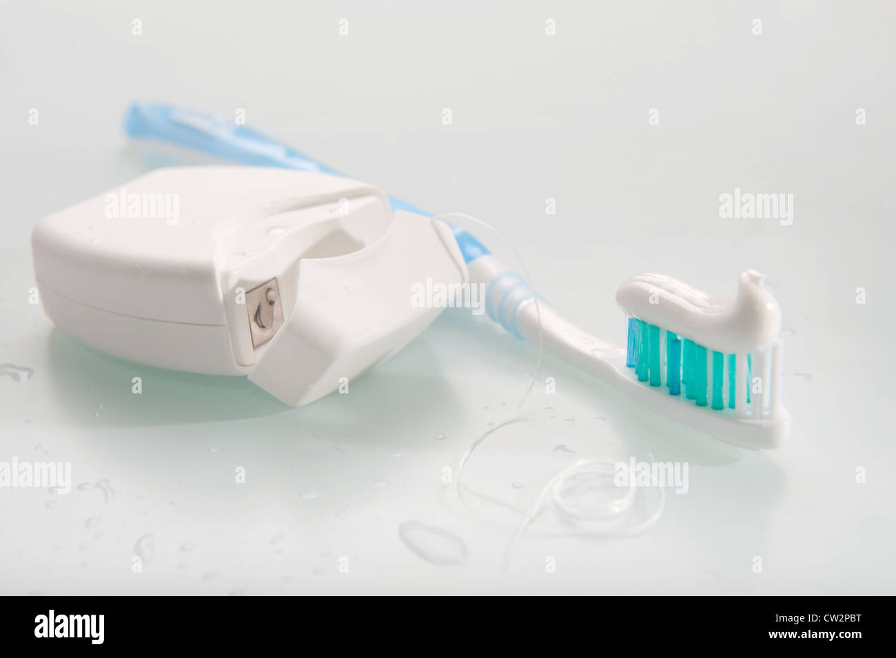 Zahnbürste mit Zahnpasta und Zahnseide auf hellem Hintergrund Stockfoto