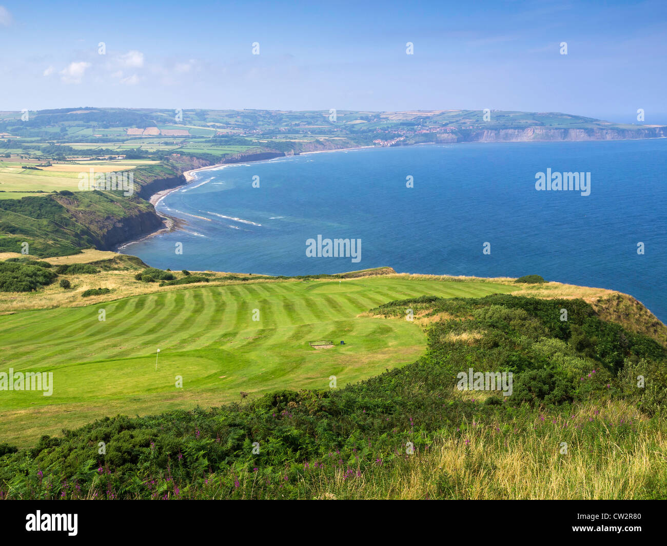 Blick über Robin Hoods Bay von der Landzunge bei Ravenscar North Yorkshhire UK mit einem Hotel-Golfplatz im Vordergrund Stockfoto