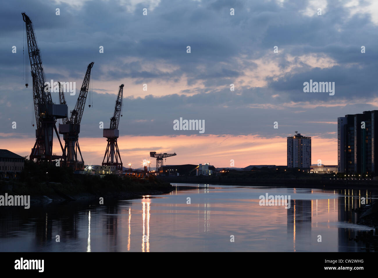Sonnenuntergang über die Krane bei BAE Systems Werft neben dem Fluss Clyde in Govan, Glasgow, Schottland, Großbritannien Stockfoto