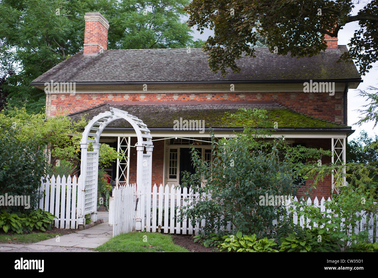 Traditionelle weiße Pickett Zaun und Arbor Tor in den Garten eines Bauernhaus in Ontario Kanada Stockfoto