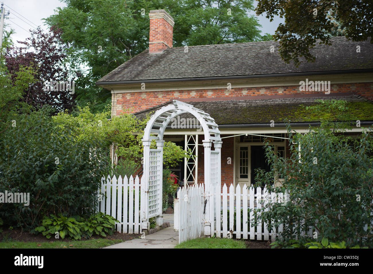 Traditionelle weiße Pickett Zaun und Arbor Tor in den Garten eines Bauernhaus in Ontario Kanada Stockfoto