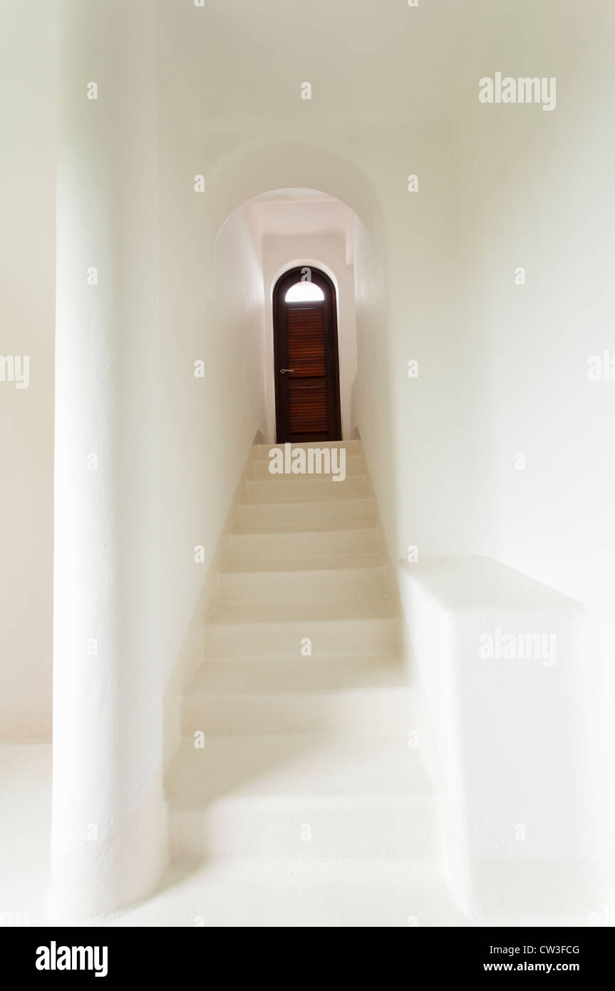 Stufen hinauf auf eine Tür in einem weißen Treppenhaus Stockfoto