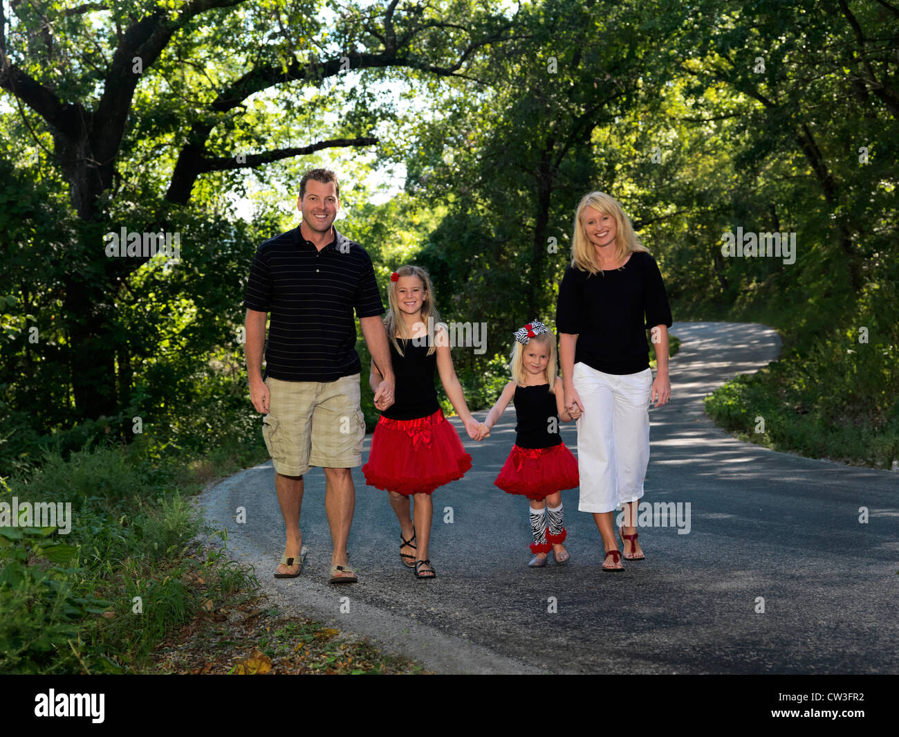 Eine junge Familie geht in Richtung der Kamera auf einer Landstraße im Süden Missouris. Stockfoto