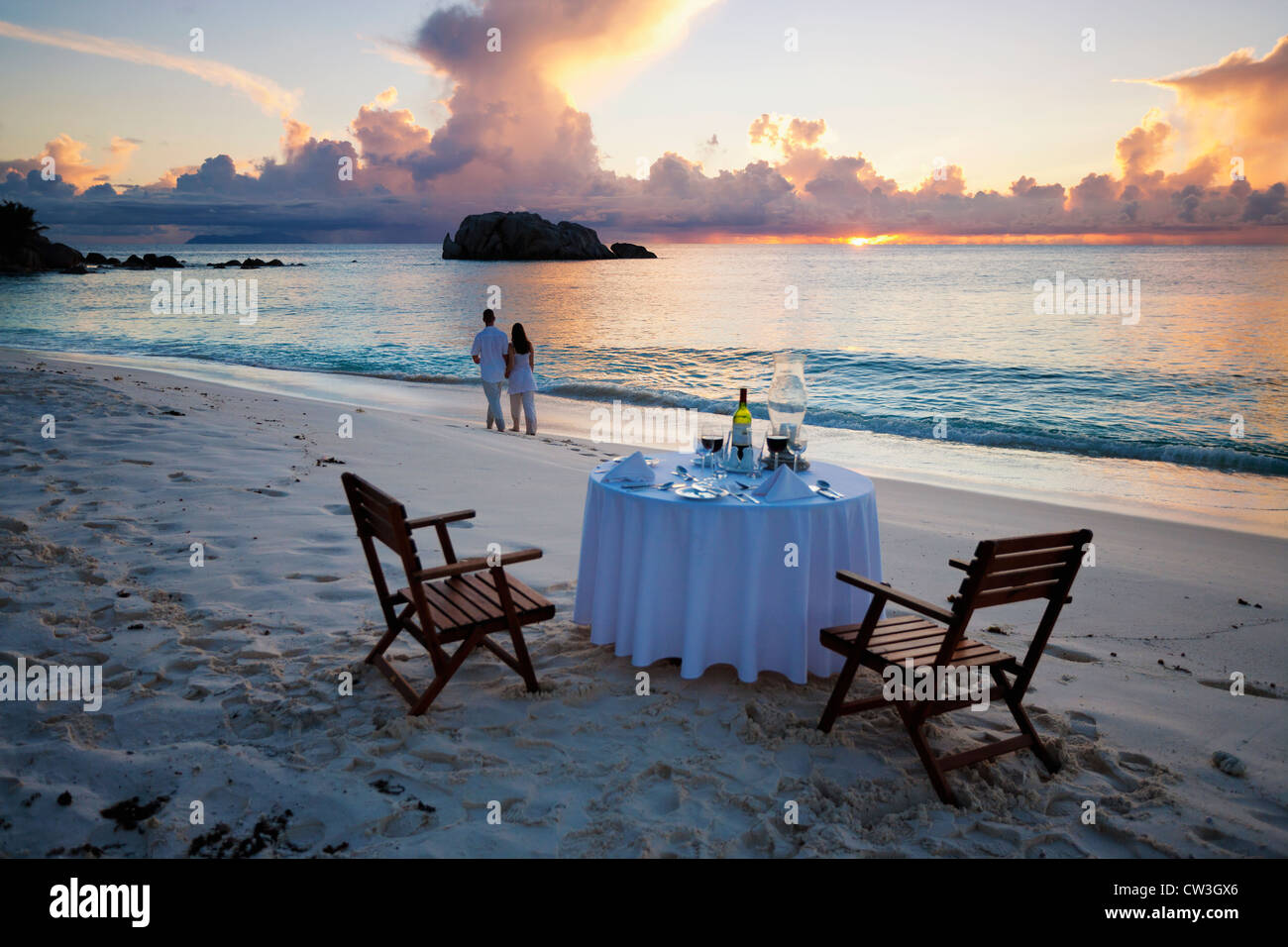 Paar zu Fuß entfernt von einem romantischen Tisch am Strand. (Modell freigegeben). (Eigenschaft freigegeben) Cousine Island. Seychellen. Stockfoto