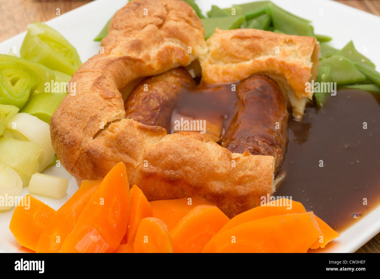 Ein klassisches britisches Gericht der Kröte in der Bohrung, die Würstchen aus Schweinefleisch gekocht in Teig dann mit Gemüse und dicken Soße serviert Stockfoto