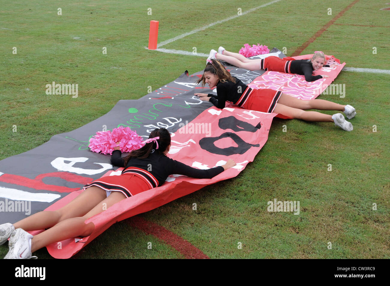 Cheerleader liegen auf einem Schild zu verhindern bei einem Fußballspiel in Bethesda, Maryland wegblasen Stockfoto