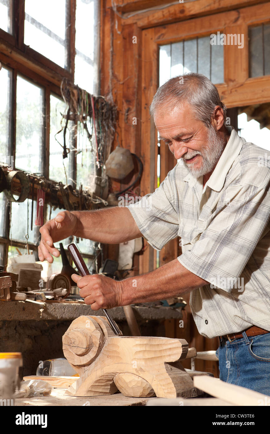 Lächelnde Tischler arbeiten mit Holz in seiner alten Schuppen Stockfoto