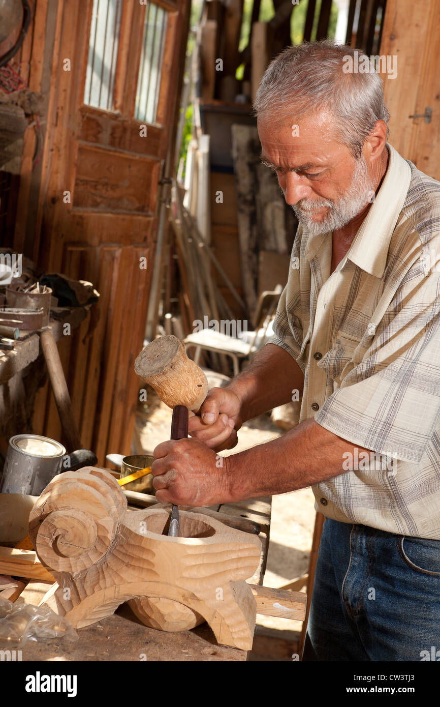 Gelernter Tischler bei der Arbeit mit Hammer und Meißel in einem alten Schuppen Stockfoto