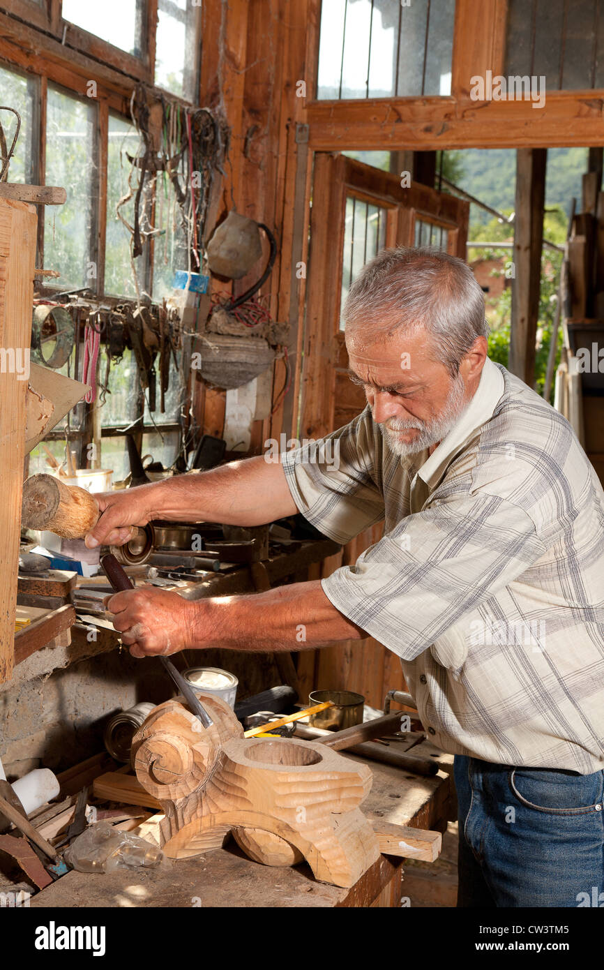 Mann, der arbeitet mit Holz vor dem Fenster von einem alten verfallenen Schuppen Stockfoto