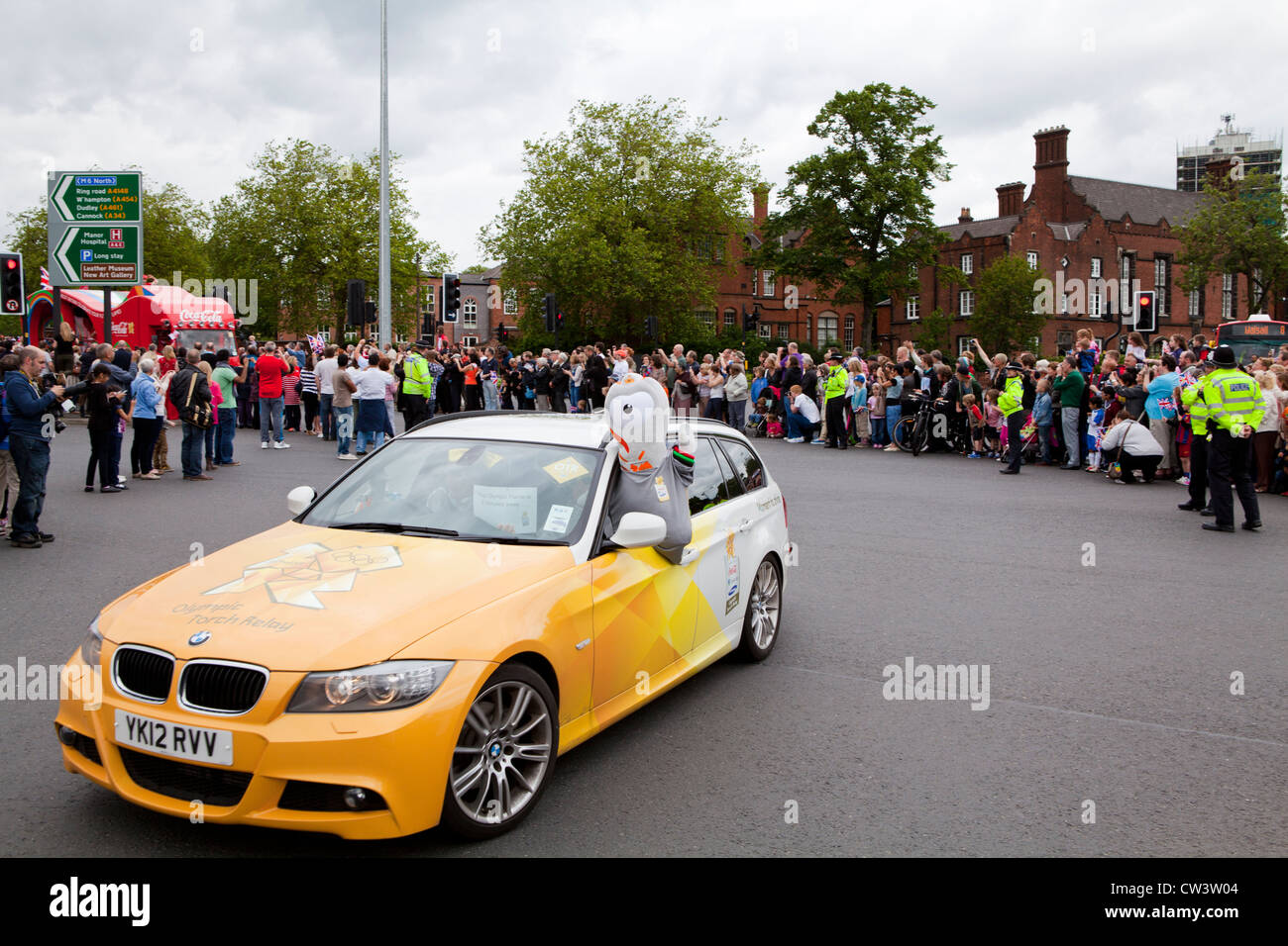 Menschenmengen säumen die Straßen von Walsall, West Midlands, die Weitergabe von die Olympische Fackel und seines Trägers vorangestellt Sponsoren erwarten Stockfoto