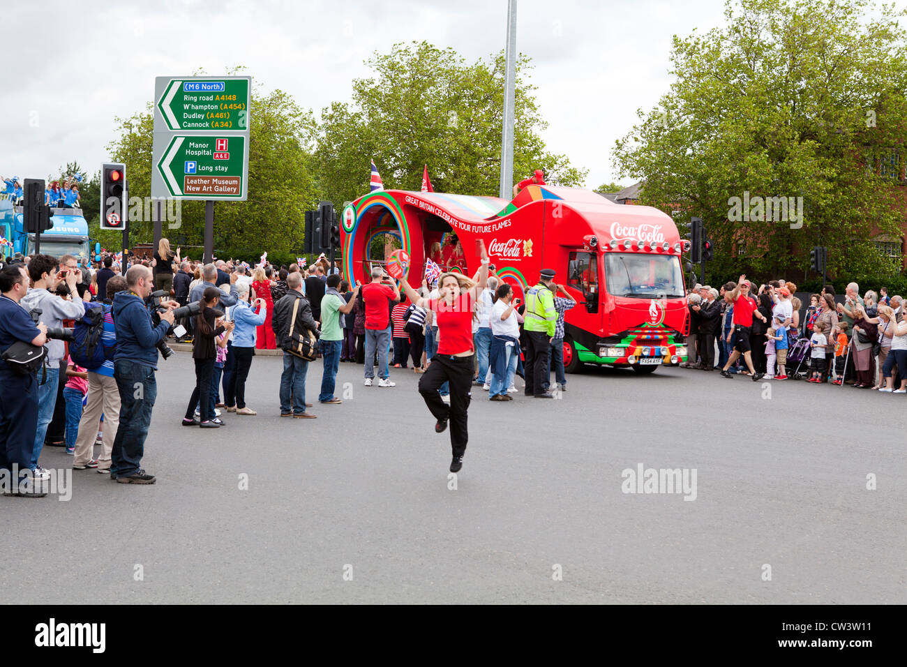 Menschenmengen säumen die Straßen von Walsall, West Midlands, die Weitergabe von die Olympische Fackel und seines Trägers vorangestellt Sponsoren erwarten Stockfoto