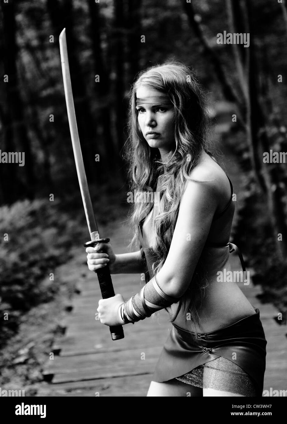 Porträt der jungen Frau mit Schwert im Wald Stockfoto