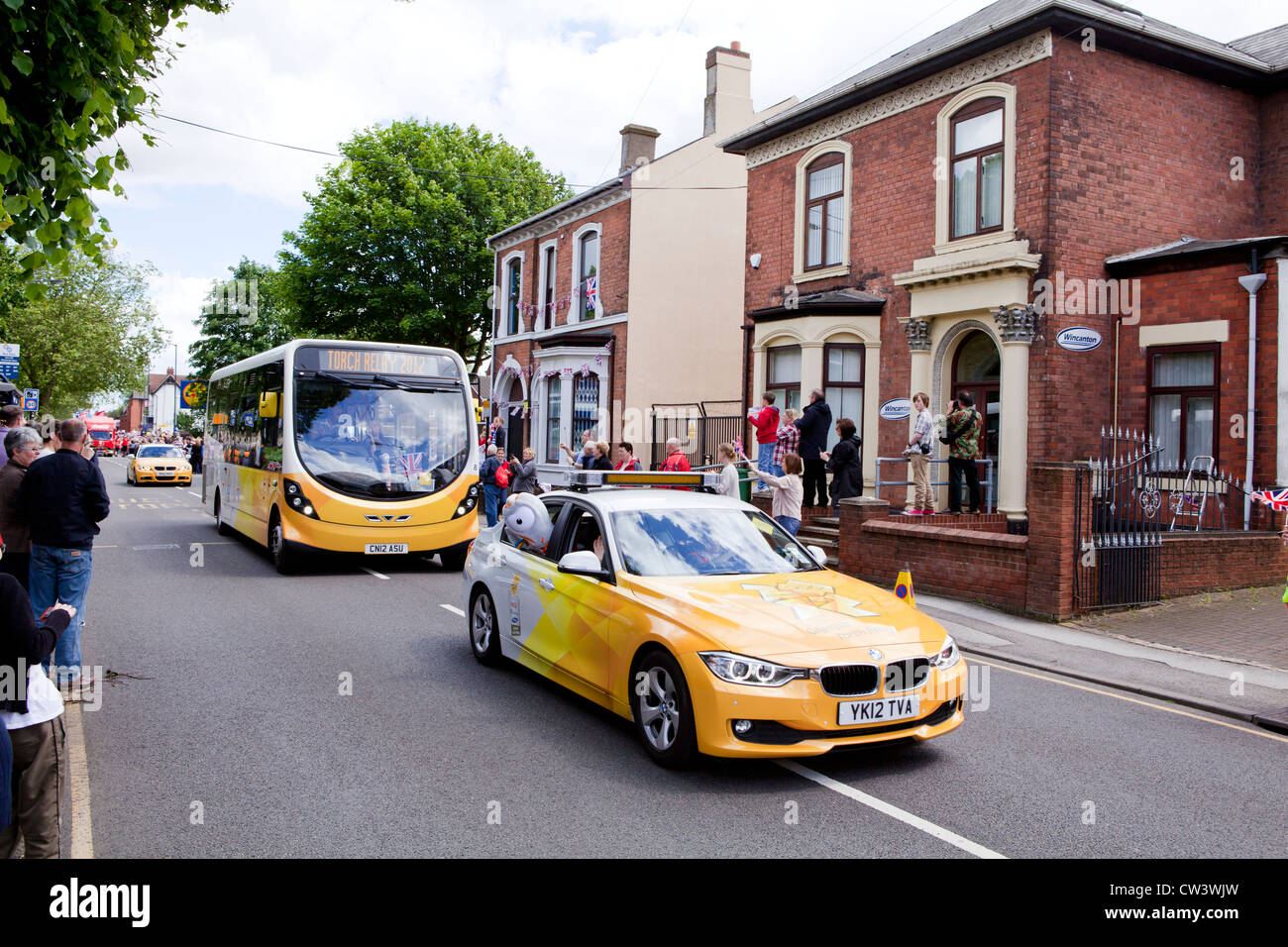 Menschenmengen säumen New Road, Willenhall, West Midlands, um die Weitergabe von die Olympische Fackel und seines Trägers vorangestellt Sponsoren erwarten Stockfoto