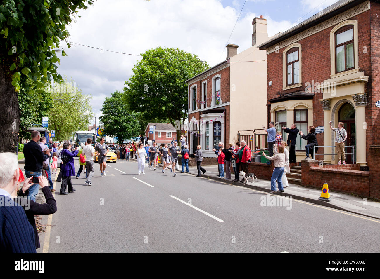 Ein olympischer Fackelträger rinnt New Road, Willenhall, West Midlands, als Teil der London 2012 Olympische Fackel Relais Route. Stockfoto