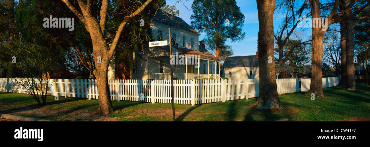 Dieses Foto typisch Vorstadthaus am Main Street USA. Es weißen Sie Lattenzaun auf schattigen Bäumen gesäumten Straße mit grünen Rasen. Stockfoto