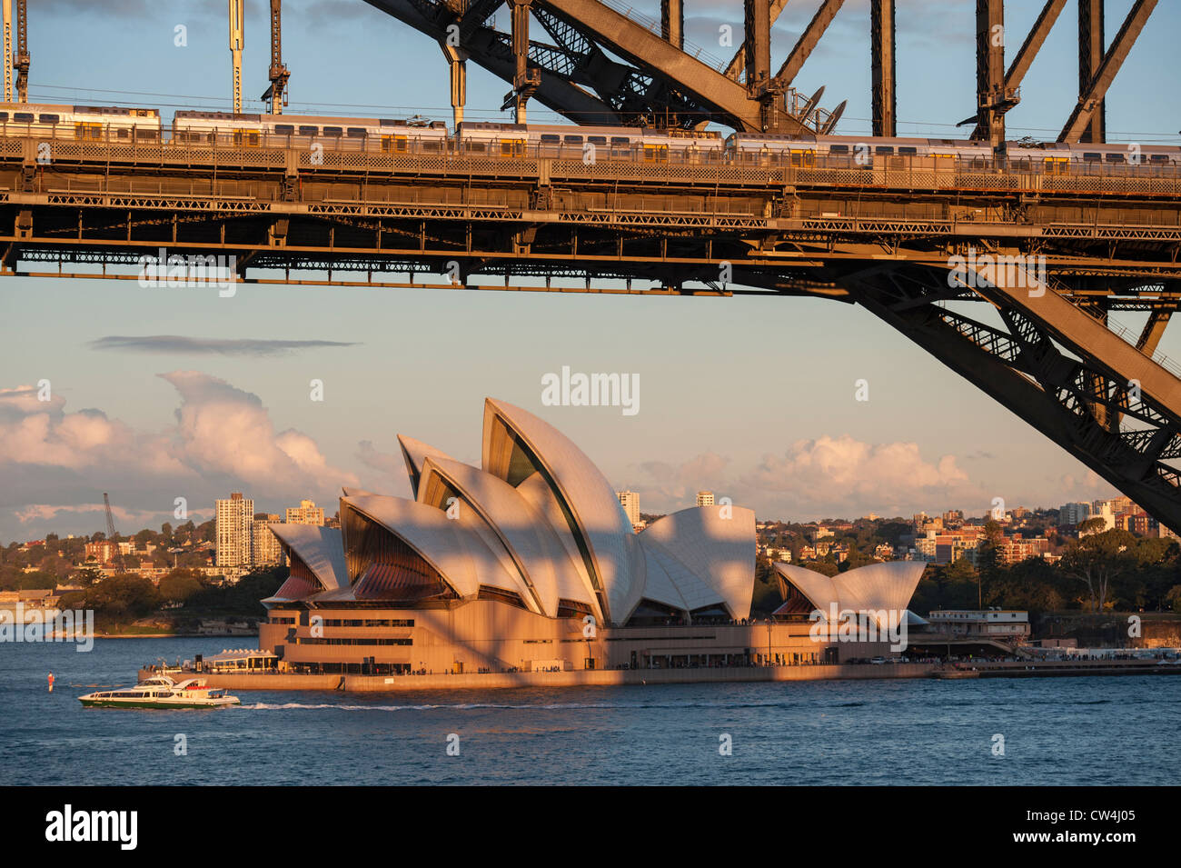 Segeln unter der Sydney Harbour Bridge mit Blick auf das Opernhaus bei Sonnenuntergang. Stockfoto