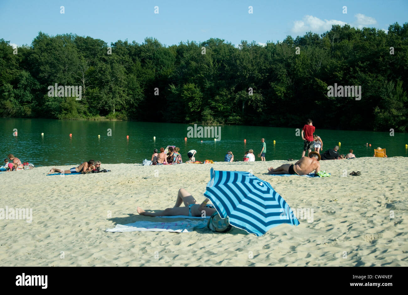 Sommergäste genießen eine landeinwärts, Baden, See und seine "importiert" Sandstrand in Lupiac, Südwest-Frankreich Stockfoto