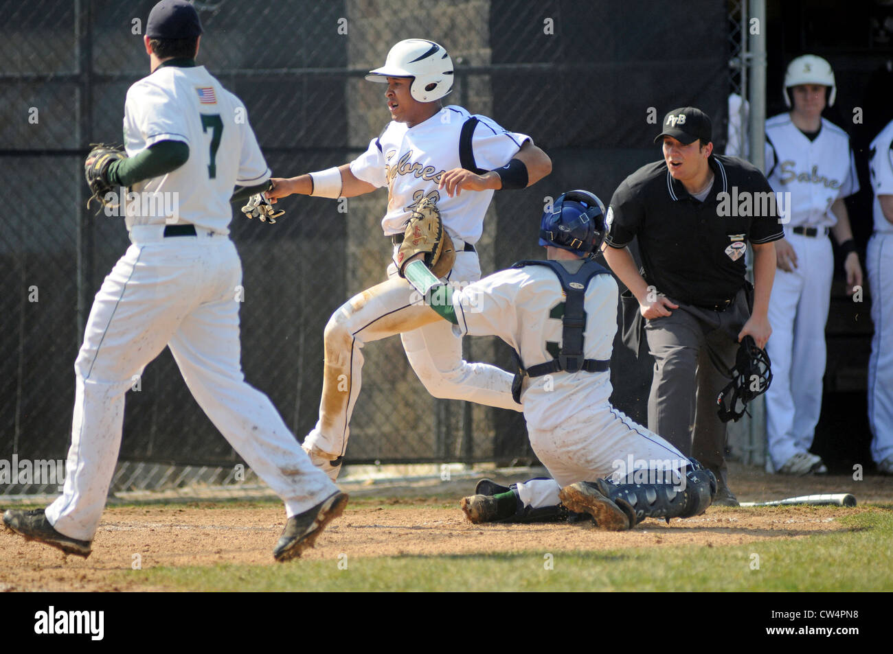 Baseball Catcher tags ein Läufer wie der Schiedsrichter seine Entscheidung und die anstehenden Anruf während eines High School Spiel betrachtet. USA. Stockfoto