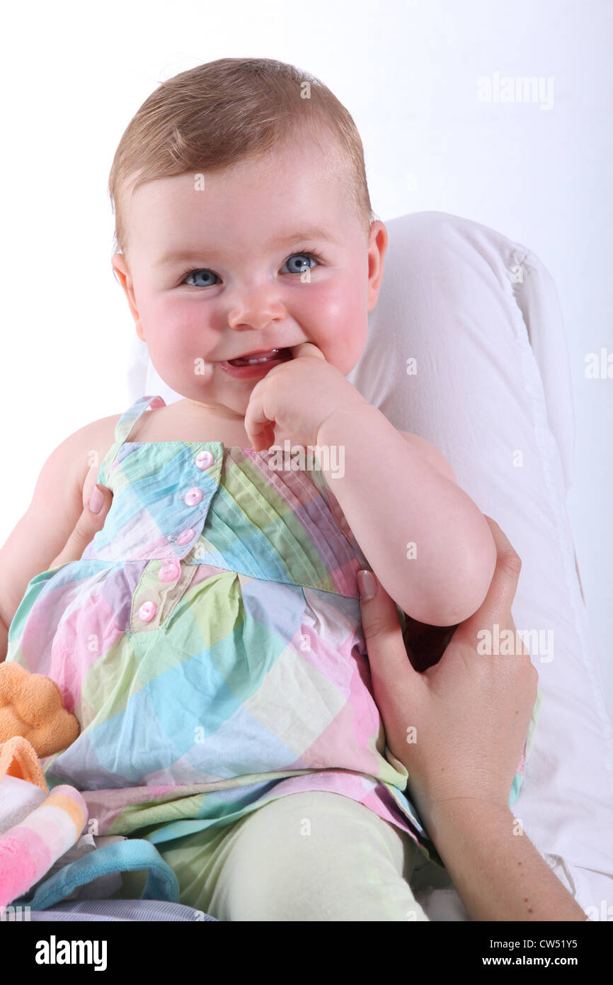 blonde Baby trägt ein buntes Kleid und lächelnd Stockfoto