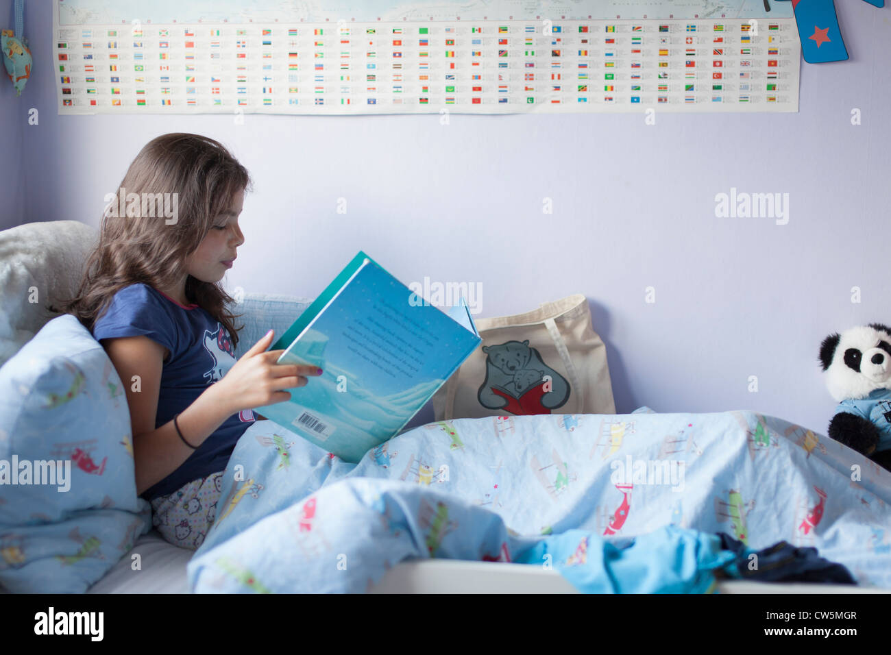 Junges Mädchen, 10, liest im Bett Stockfoto