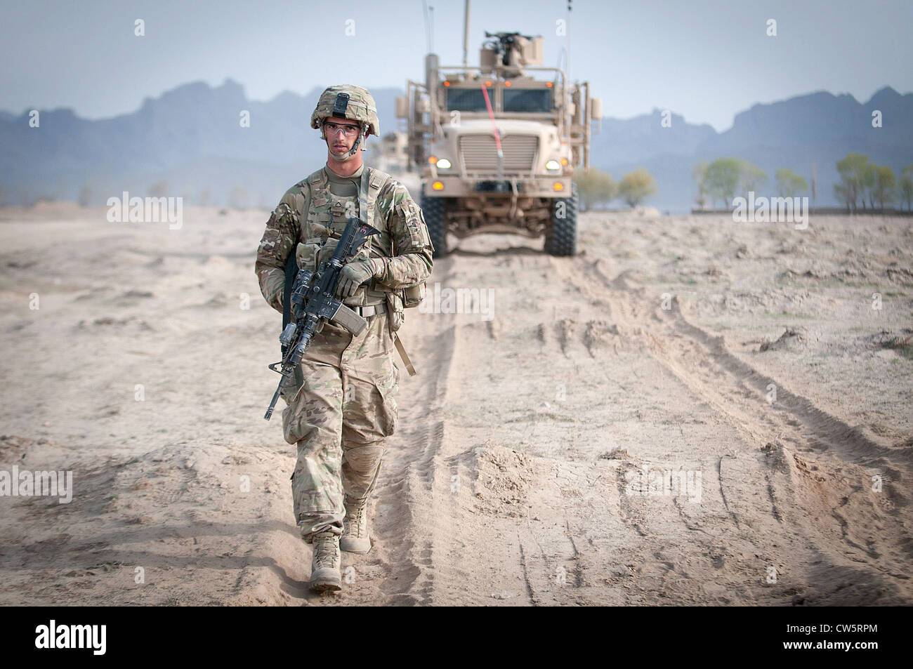 Ein US-Army Fallschirmjäger kehrt zu seinem Stützpunkt in Afghanistan Ghazni Südprovinz vor einer Mine Resistant Ambush Protected Fahrzeug oder MRAP 8. April 2012. Anfang April übernahm seine Brigade der polnischen Mission in der Gegend. Stockfoto