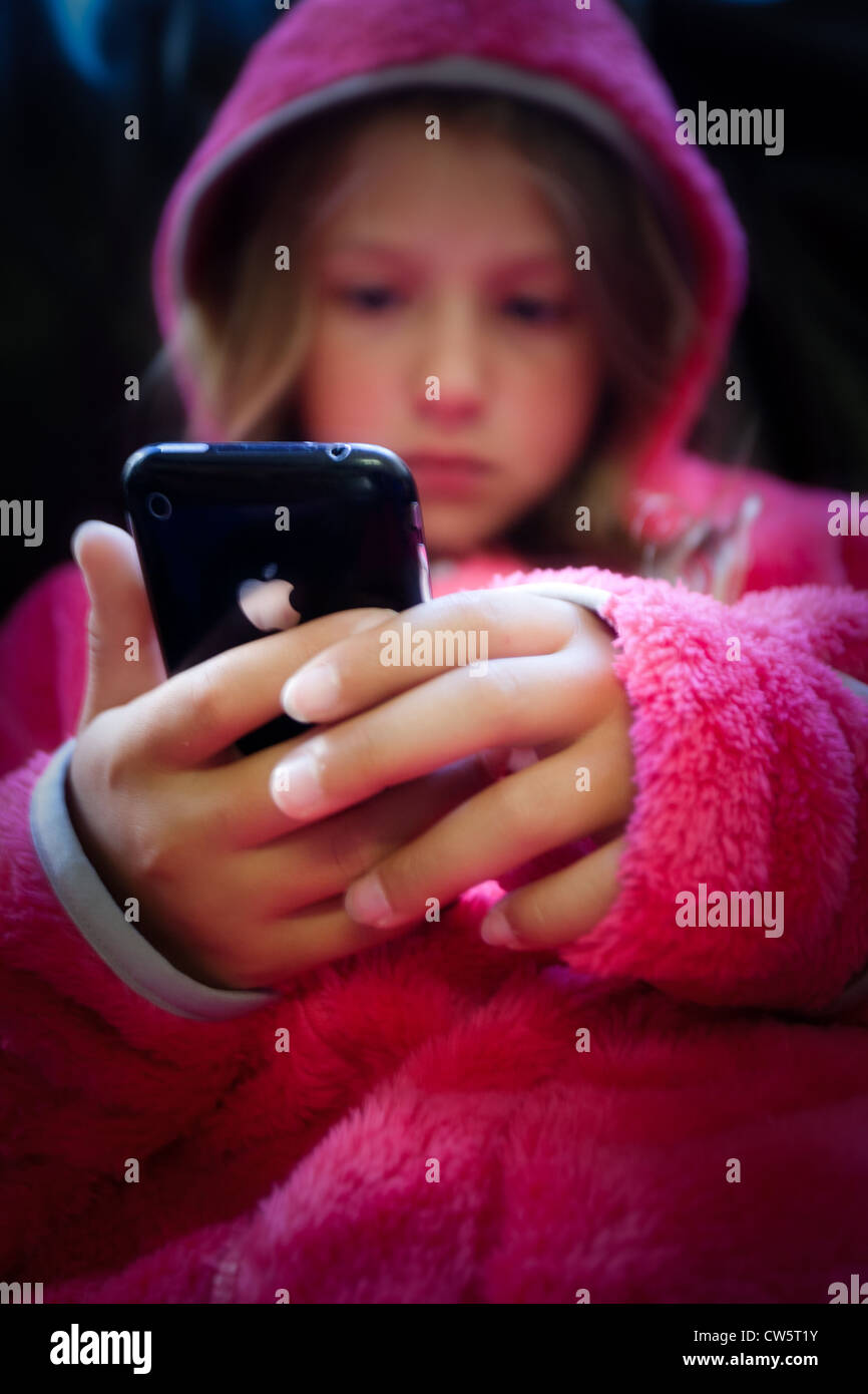 Ein junges Mädchen in einem rosa hoody Blick auf ein Apple iPhone Stockfoto