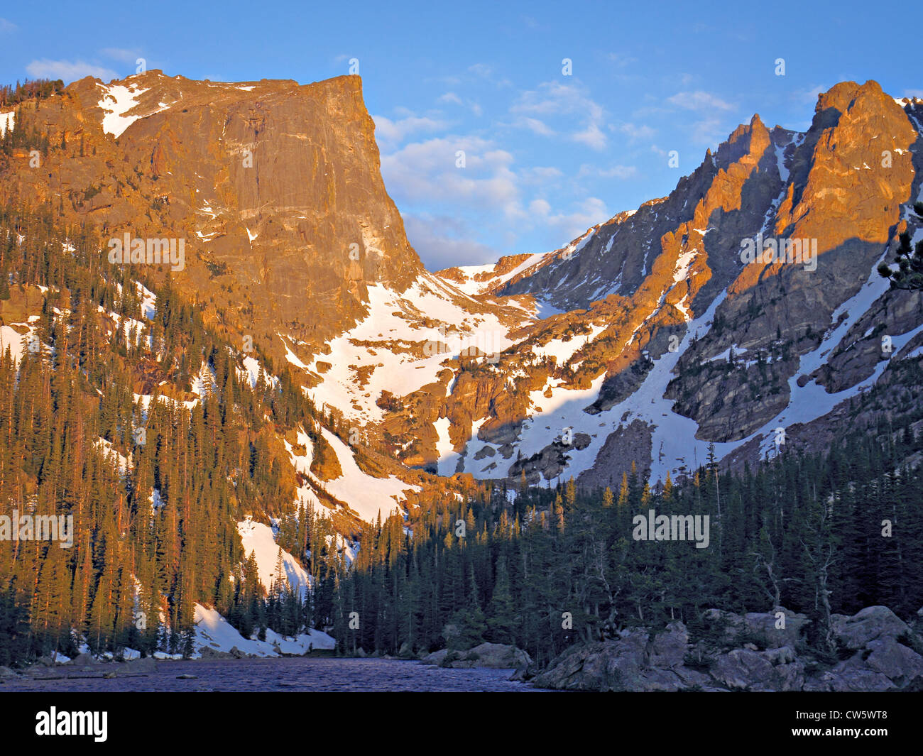Granit Bergspitzen mit Schnee und Kiefern im unteren Pisten in orange Morgenlicht gesehen vom Ufer des Sees gebadet Stockfoto