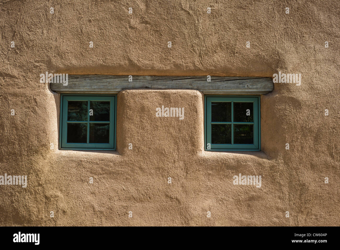 Paar kleine quadratische Fenster unter Holzbalken im alten Adobe-Stil Haus Santa Fe New Mexico USA Stockfoto