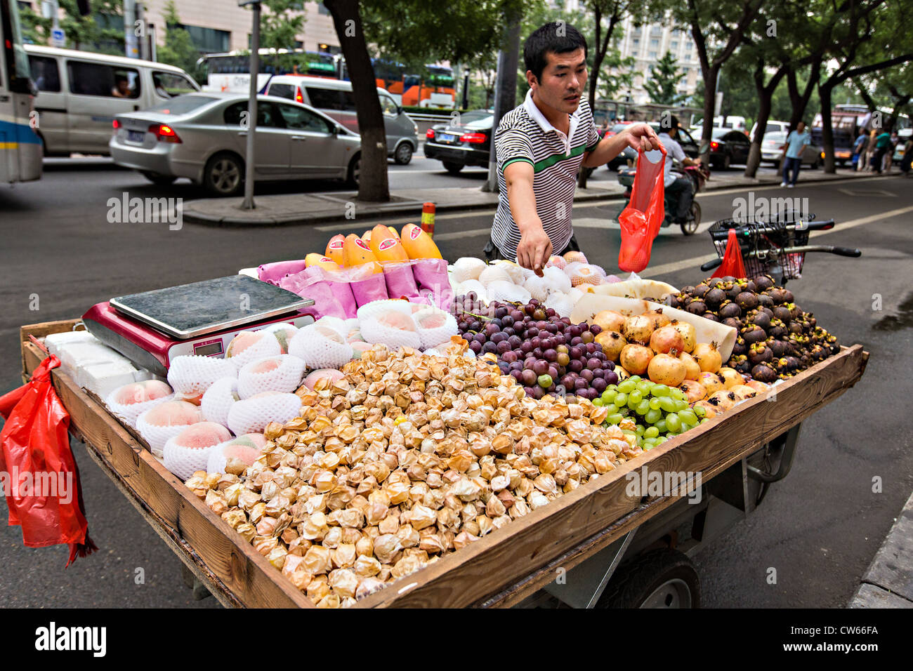 Ein Obsthändler an einer befahrenen Straße in Peking, China Stockfoto