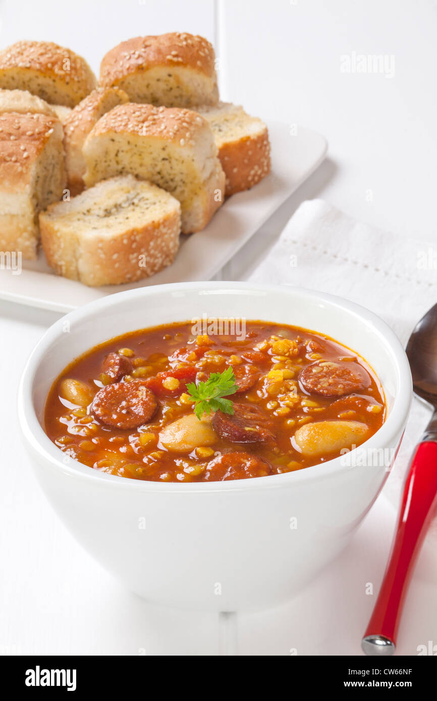 Spanische Chorizo Suppe mit roten Linsen, Tomaten und Butter Bohnen, mit Knoblauchbrot serviert. Stockfoto