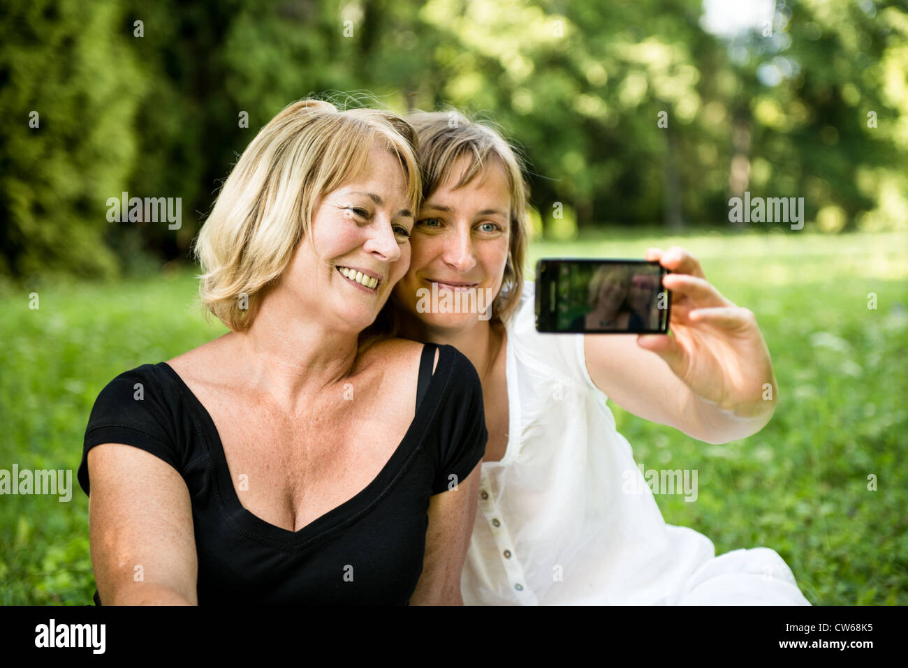 Erwachsene Tochter und Mutter senior nehmen Bild mit Handy Stockfoto