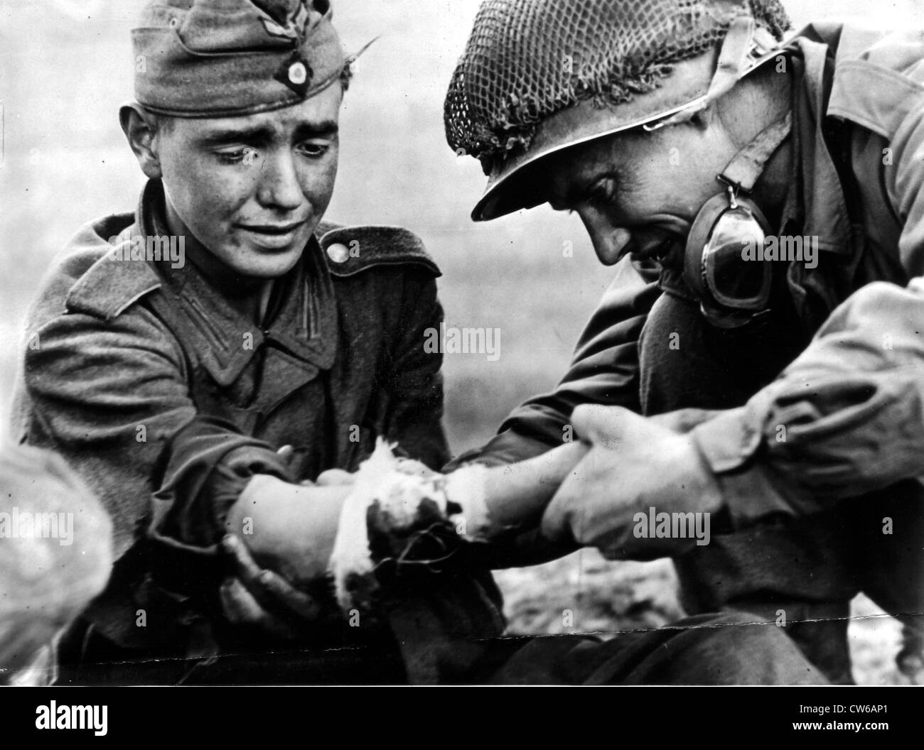 Ein US-Soldat schaut den verletzten Arm eines deutschen Soldaten in Frankreich (Herbst 1944) Stockfoto