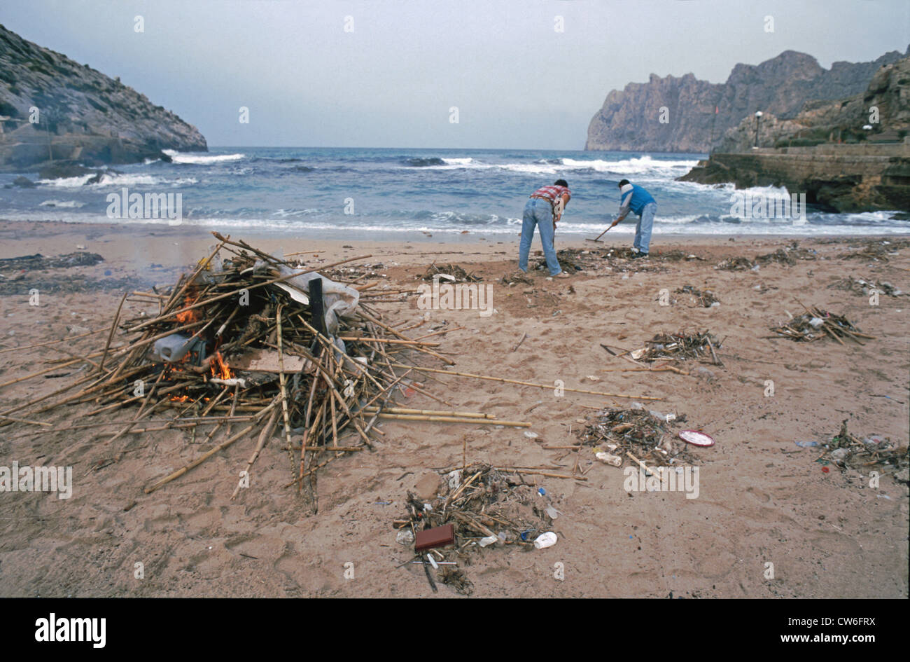 zwei Männer sammeln und brennen Flotsom und Müll am Strand, Spanien, Mallorca, Balearen, Spanien Stockfoto