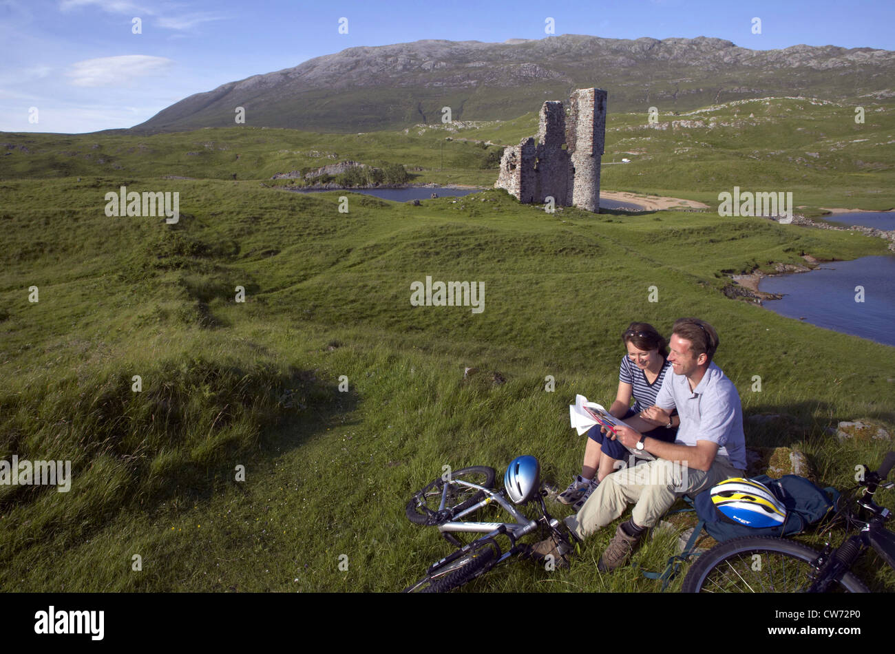 Paar erholsame nach Bikeride neben Ardvreck Castle, Loch Assynt, Großbritannien, Schottland, Sutherland Stockfoto