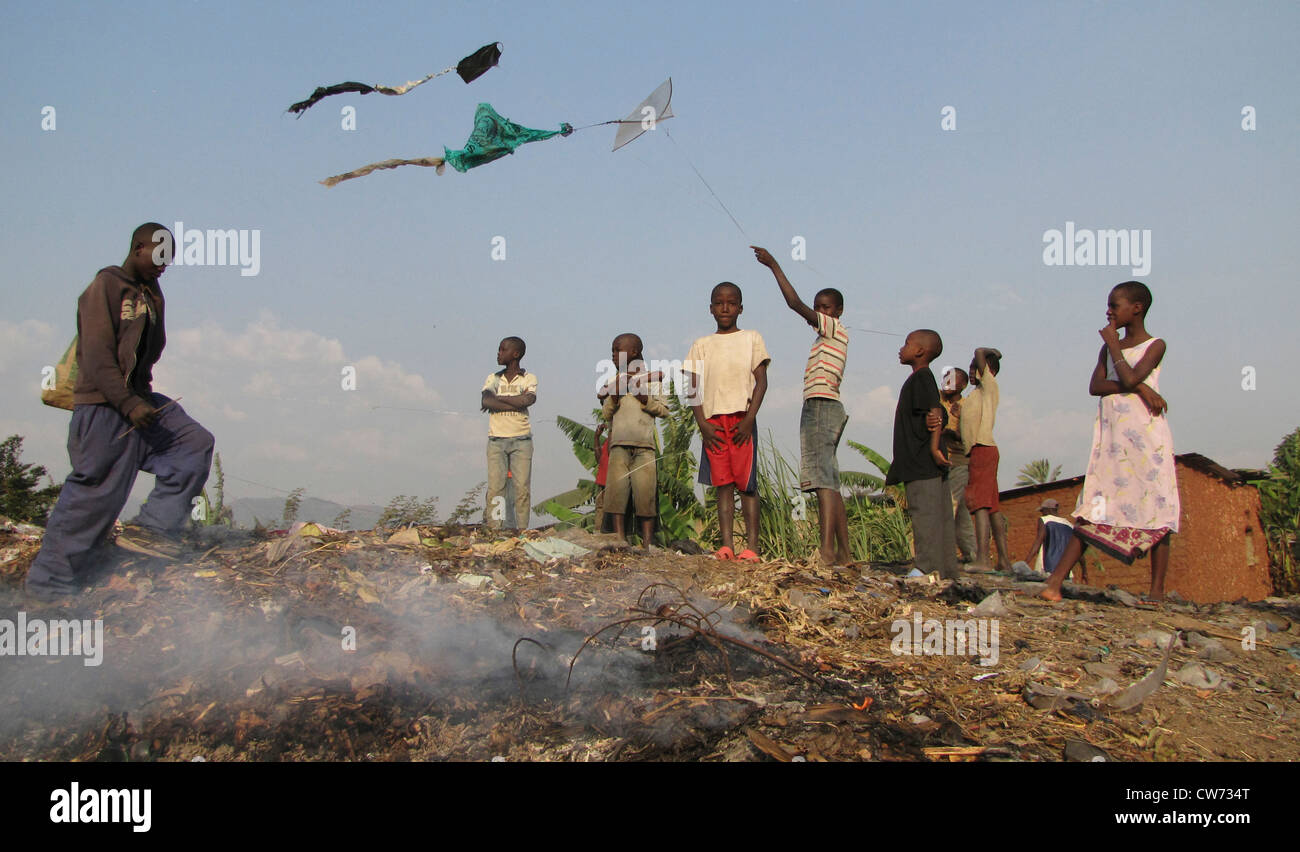 Kinder, die fliegenden Drachen über eine Deponie in den Slums, während Rauch steigt aus der Verbrennung von Müll, Burundi, Bujumbura Mairie, Buyenzi, Bujumbura Stockfoto