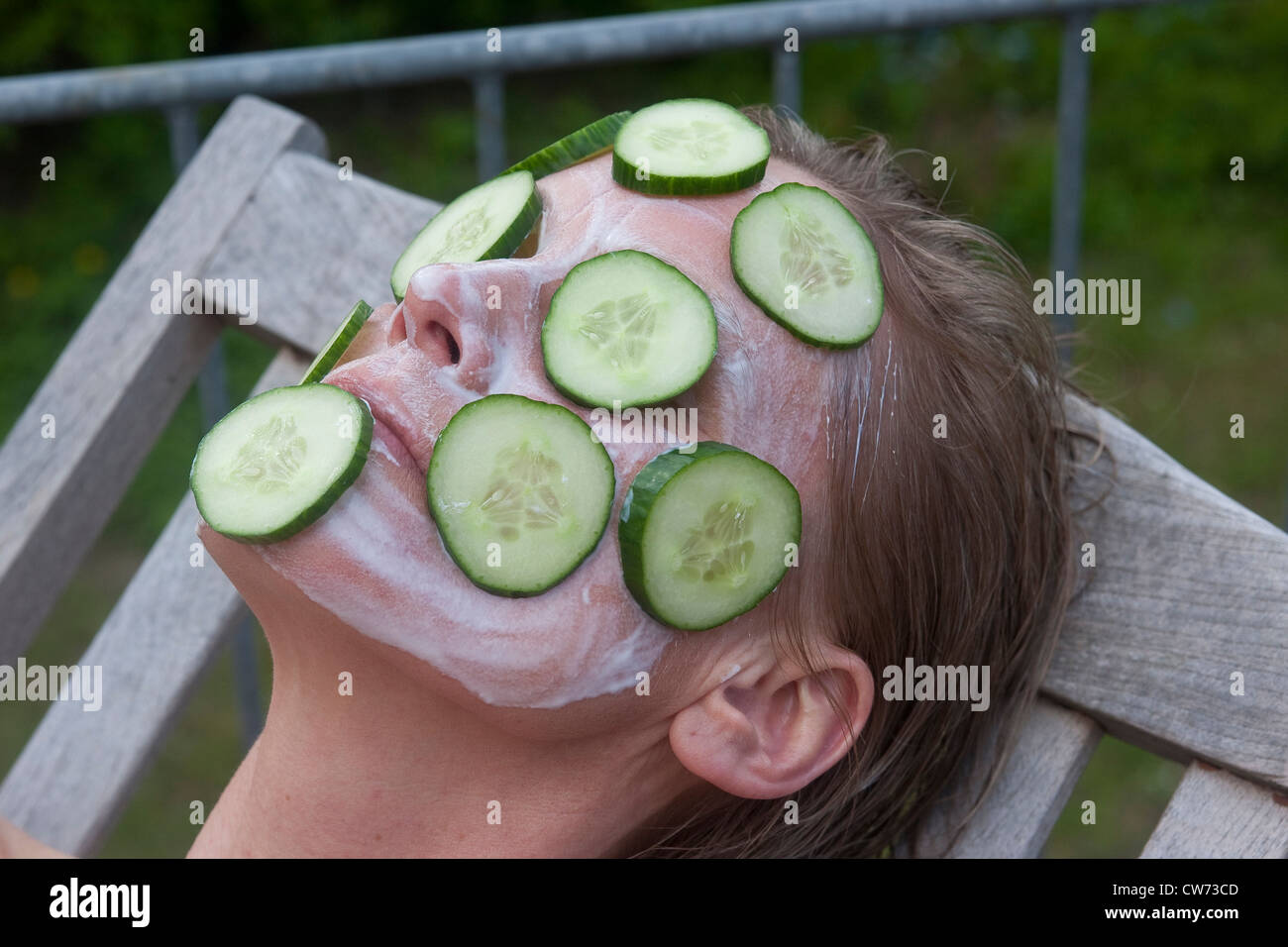 Frau liegend auf einem Segeltuch Stuhl mit einem Gurken-Maske Stockfoto