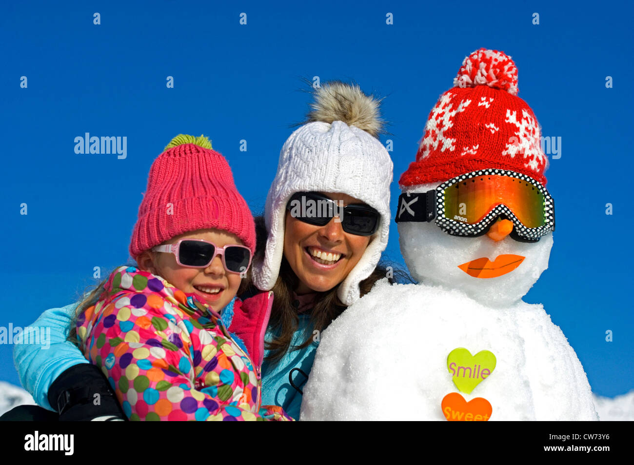 Mutter und Tochter im Winterurlaub mit Schneemann, Frankreich Stockfoto