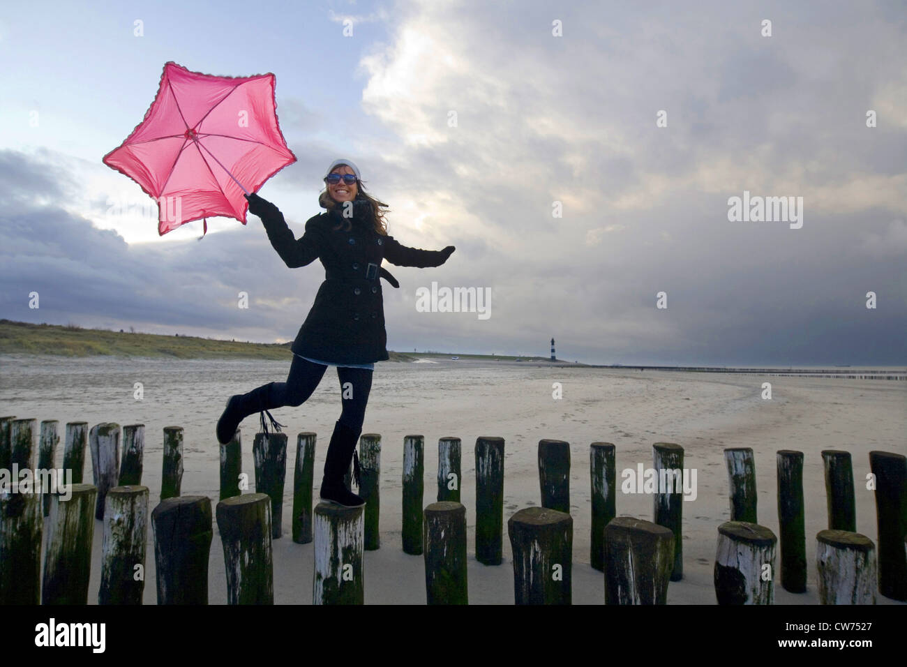 junge Frau mit rosa Regenschirm balancieren auf Sporn Deiche, Niederlande, Zeeland, Breskens Stockfoto