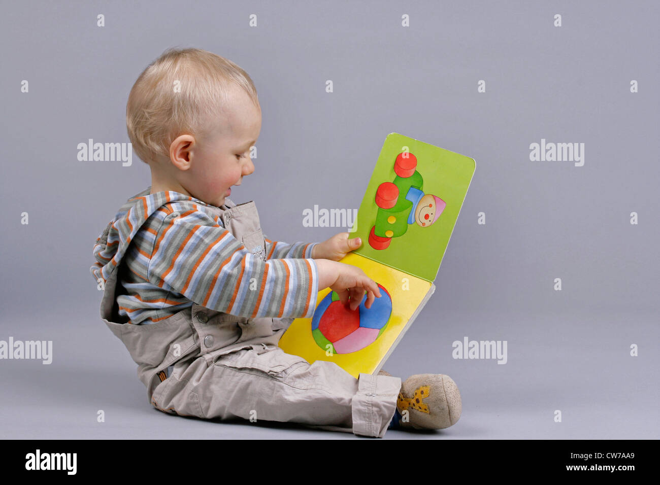 kleiner Junge auf der Suche in einem Bilderbuch, Deutschland Stockfoto