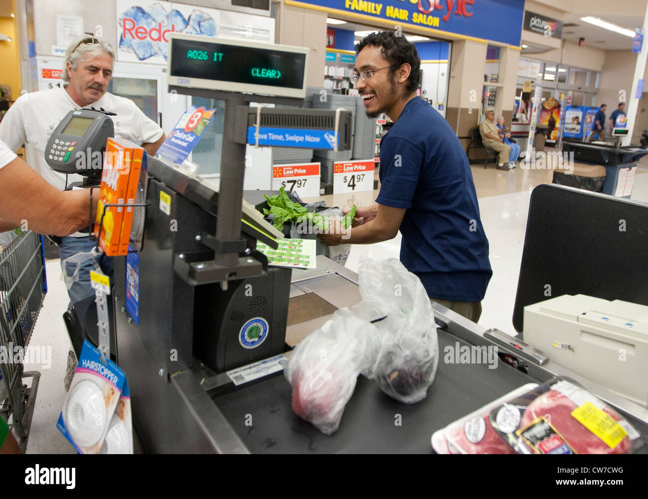 Lächelnde junge Hispanic männlichen Kasse klingelt Produkte für Kunden auf ein Wal-Mart Supercenter in San Marcos, Texas Stockfoto